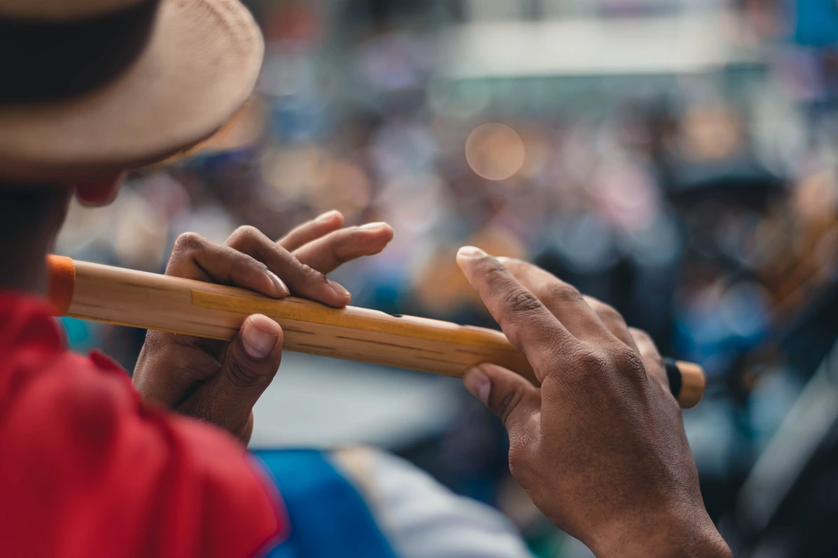 Close-up of a flautist's hands on a bamboo bansuri, playing outdoors before a crowd