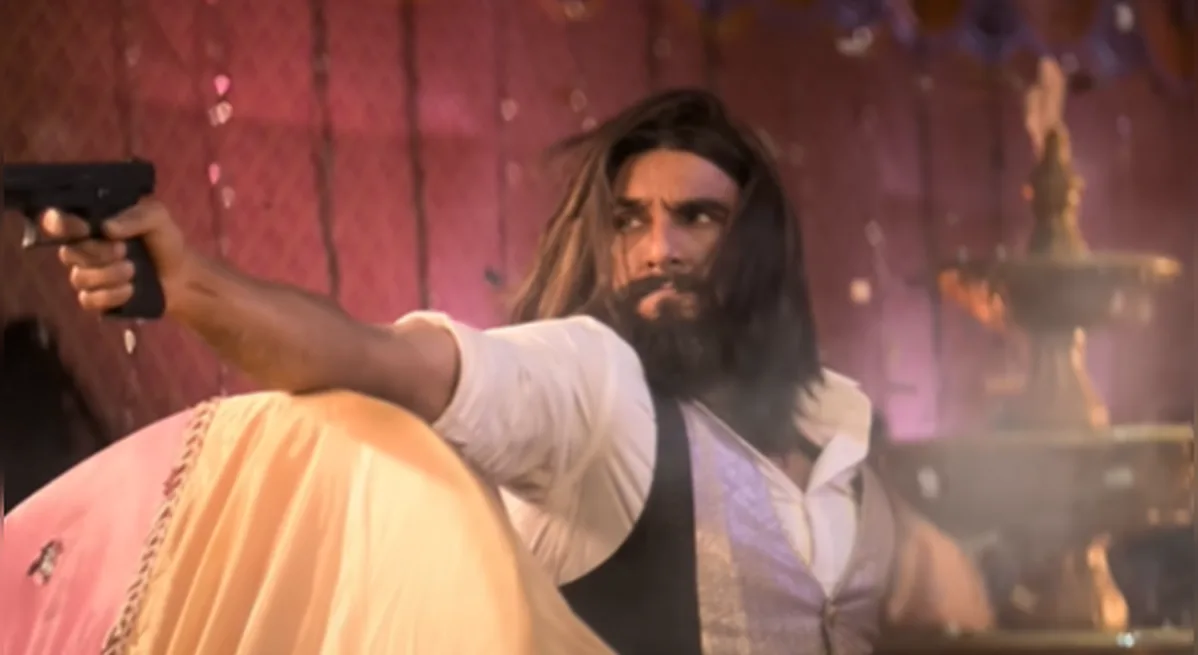 Ranveer Singh in Dhurandhar — mid-action, pistol raised, mid-stride through a haze of smoke