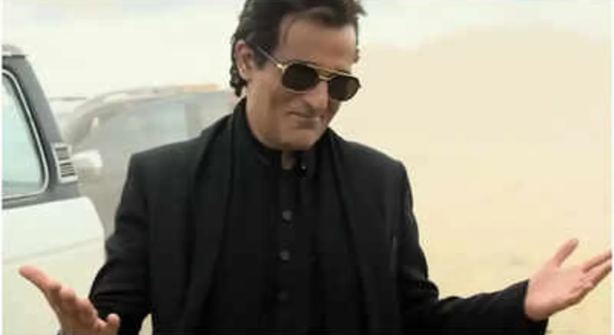 Akshaye Khanna as Rehman Dakait in Dhurandhar — dark kurta, aviators, standing before a dust-coloured backdrop