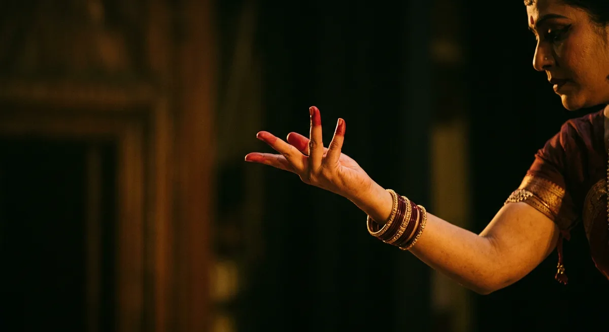 A classical dancer's expressive hand gesture in warm theatrical light